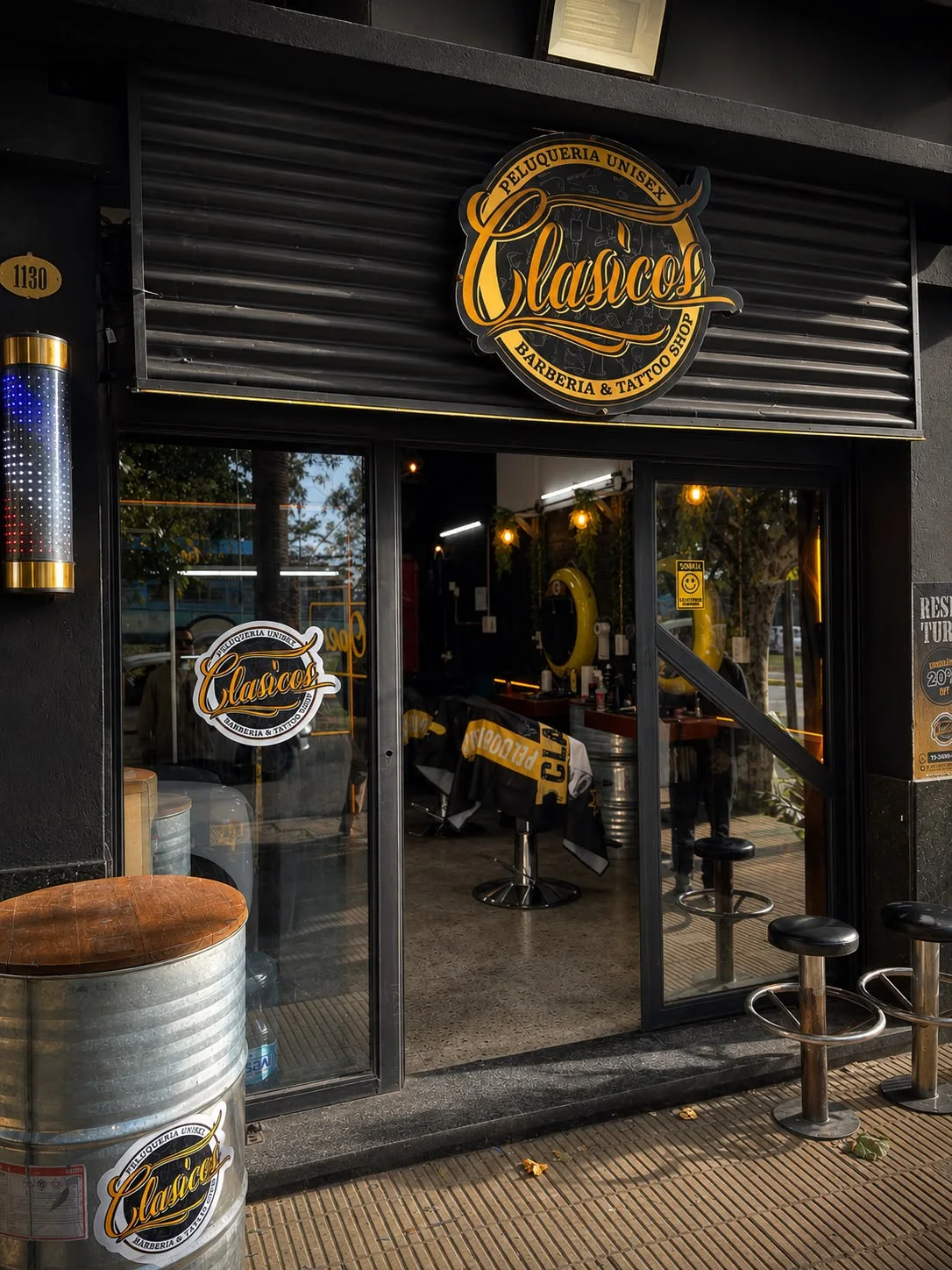 Fachada de barbería Clásicos con mesa sobre un barril y un taburete